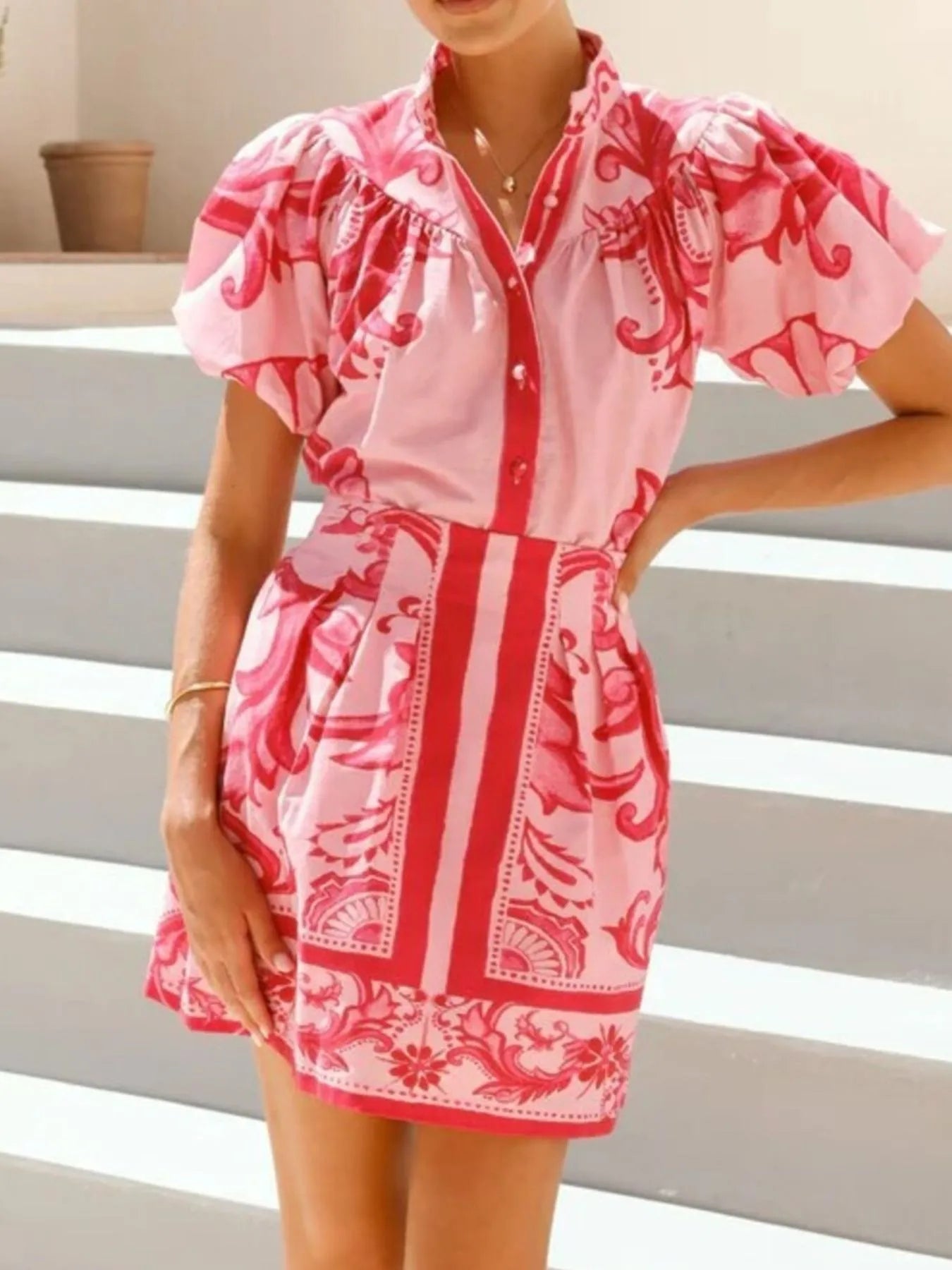 Woman wearing a pink and red floral print mini dress with puff sleeves, outdoors