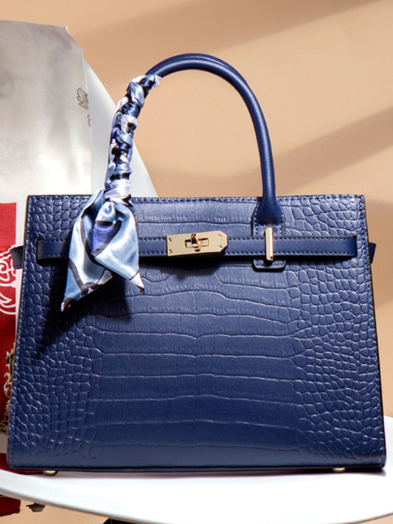 Blue crocodile textured handbag with gold hardware and silk scarf handle accent