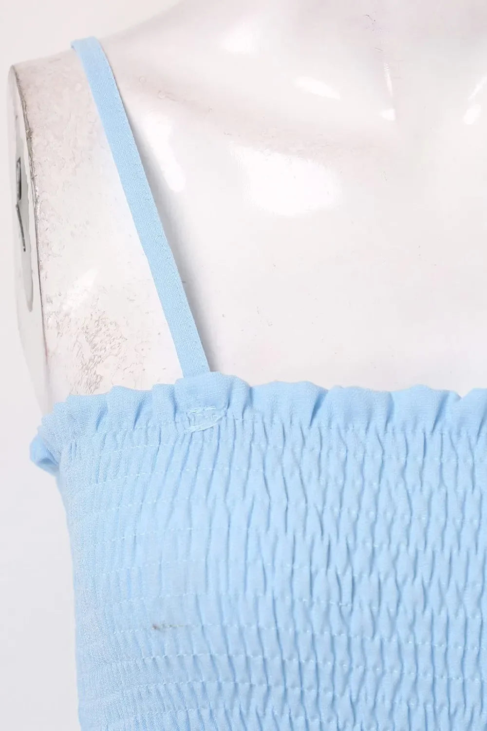Close-up of light blue smocked fabric dress with thin spaghetti strap on mannequin