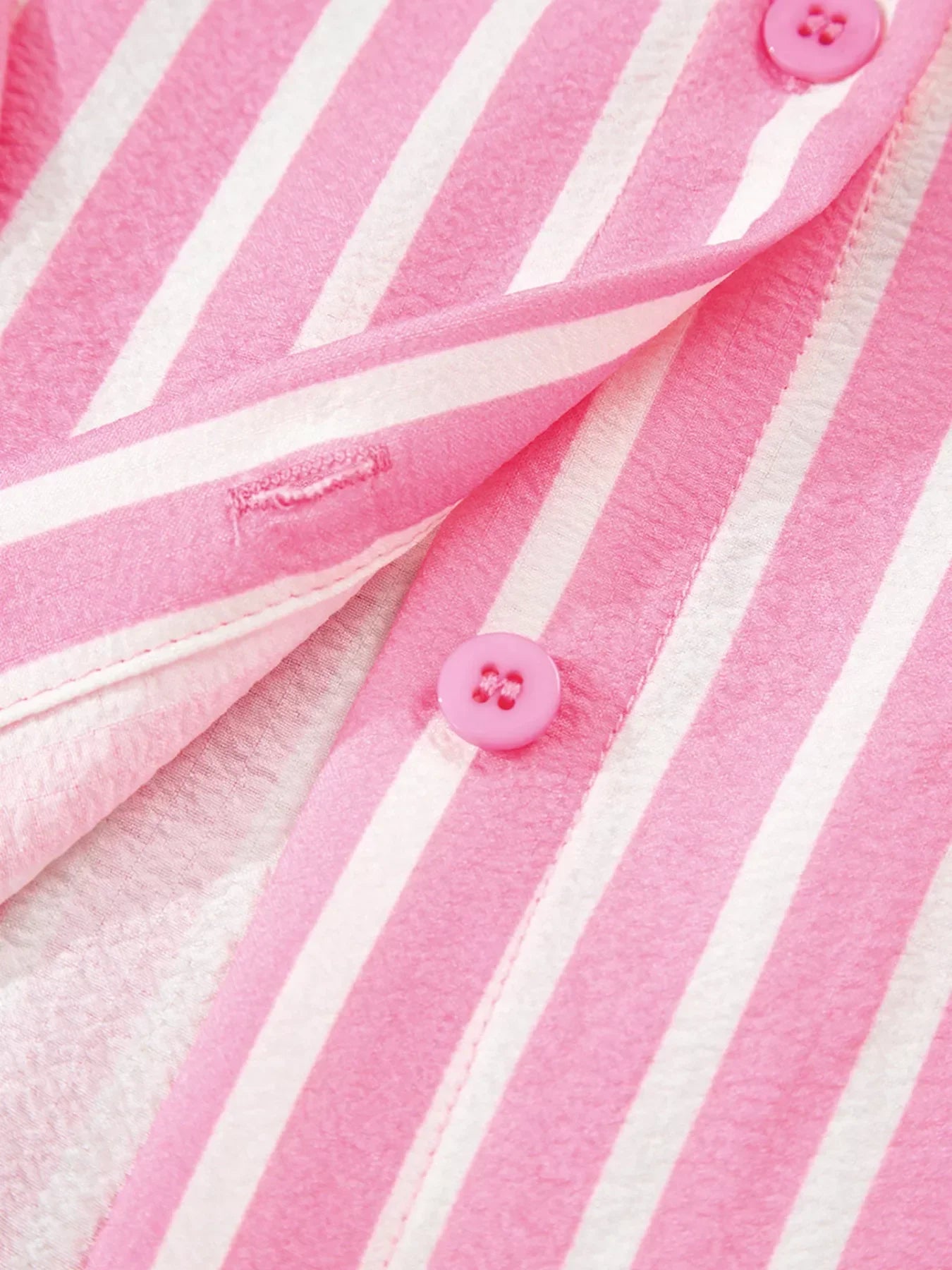 Close-up of pink and white striped fabric with pink buttons and buttonholes
