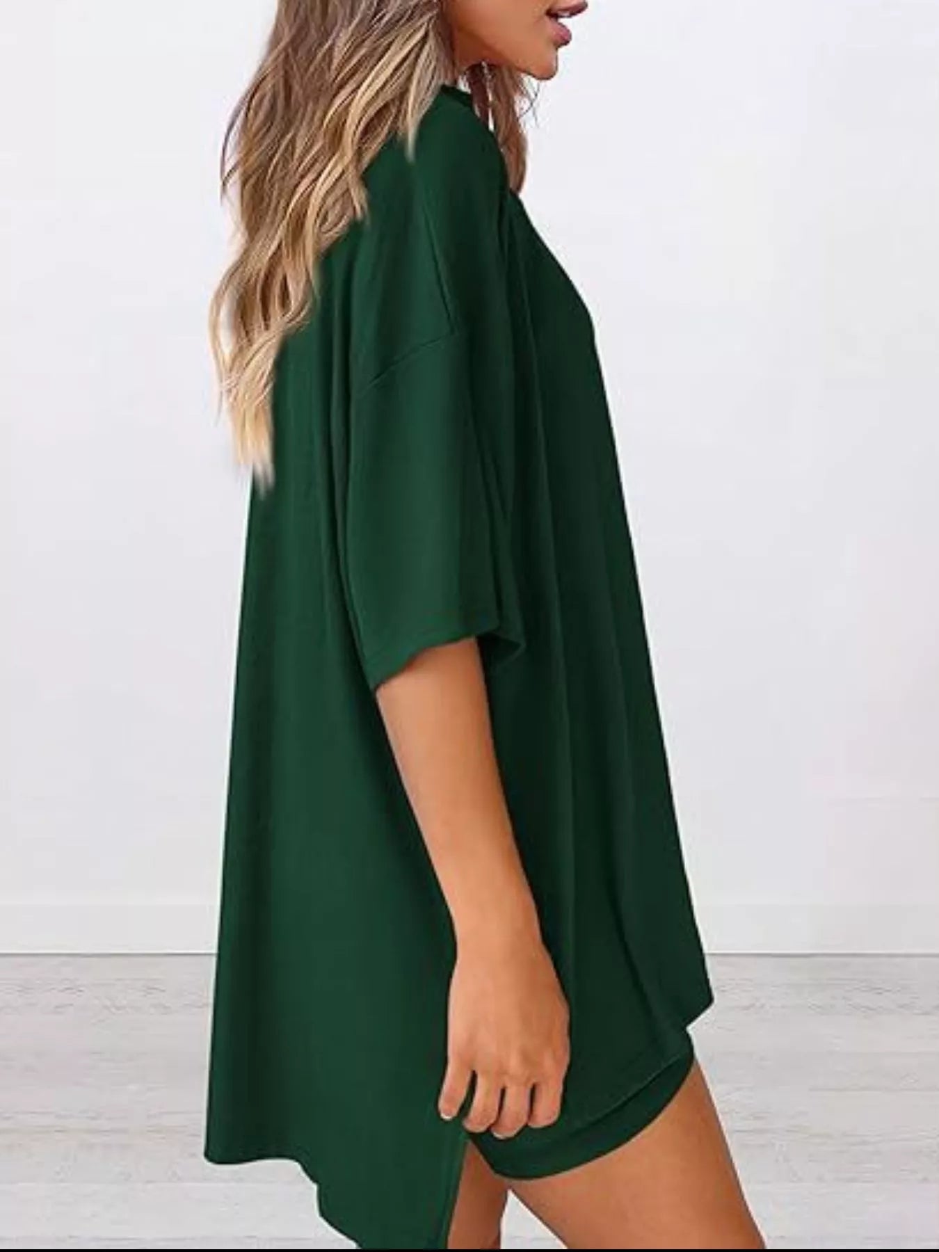 Woman wearing oversized dark green t-shirt dress with short sleeves and loose fit
