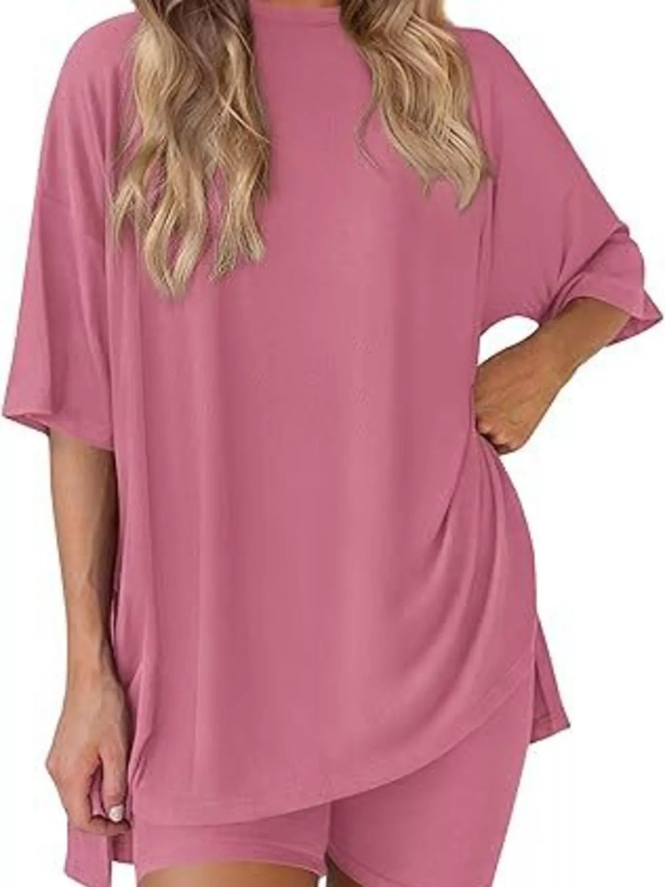 Woman wearing loose pink lounge set with short sleeves and matching shorts