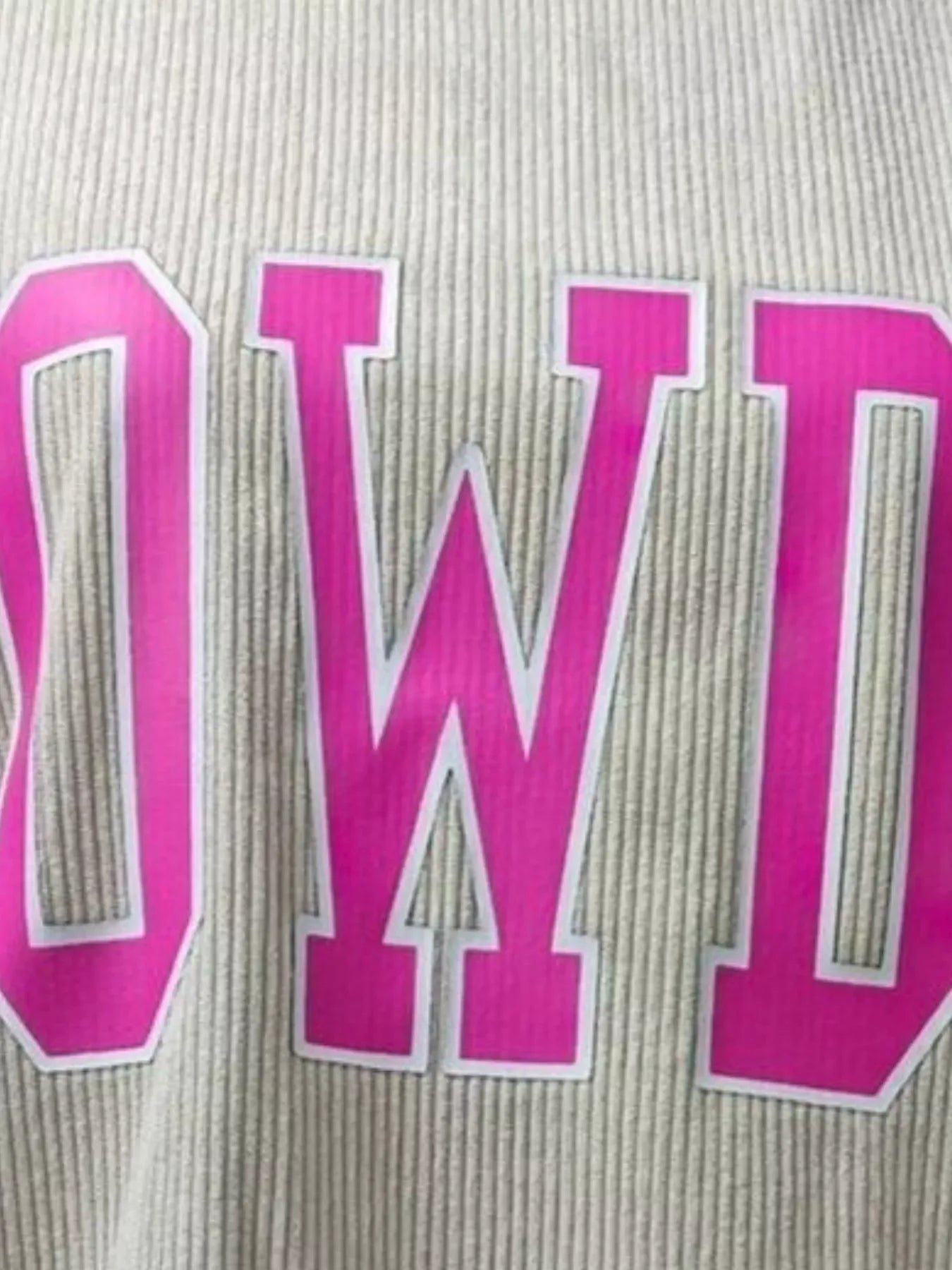 Close-up of pink varsity-style letters on beige ribbed fabric