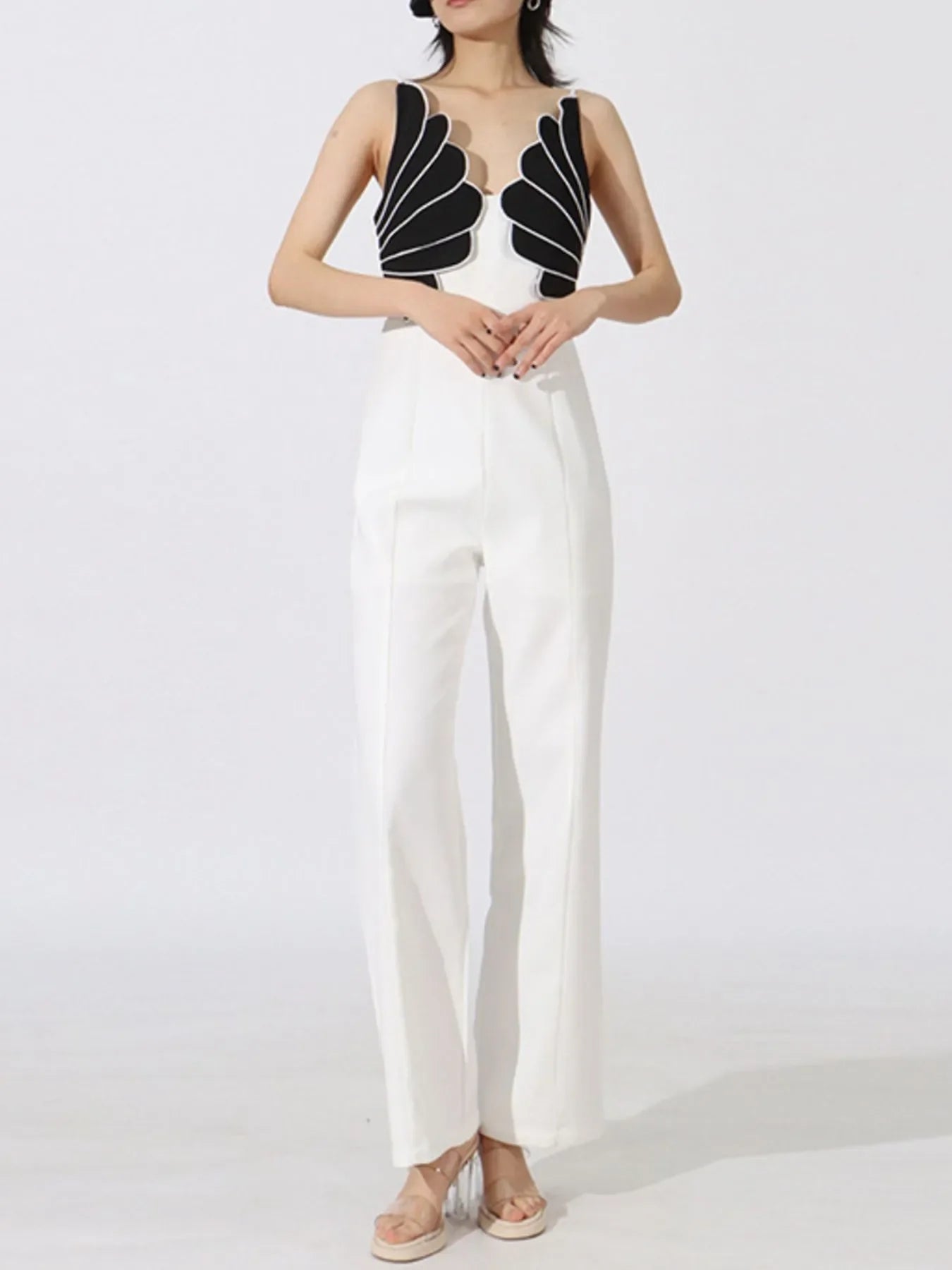 Woman wearing white wide-leg pants and a black and white scallop patterned sleeveless top