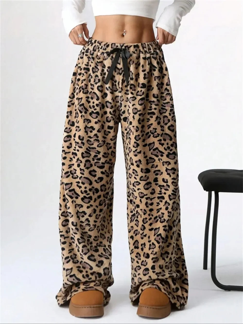 Woman wearing leopard print wide-leg lounge pants with black drawstring and brown slippers