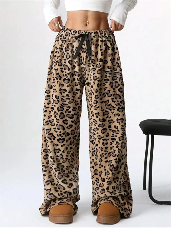 Woman wearing leopard print wide-leg lounge pants with black drawstring and brown slippers