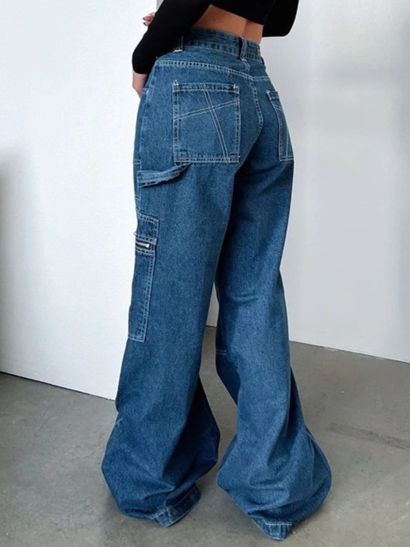Woman wearing high-waisted wide leg baggy denim jeans with cargo pockets, trendy fashion.