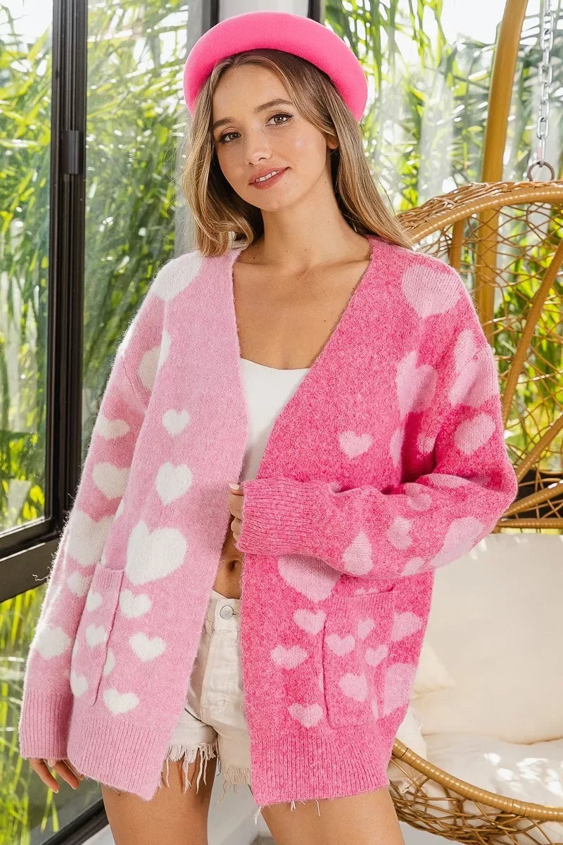 Young woman wearing a pink and light pink heart-patterned cardigan and bright pink beret indoors