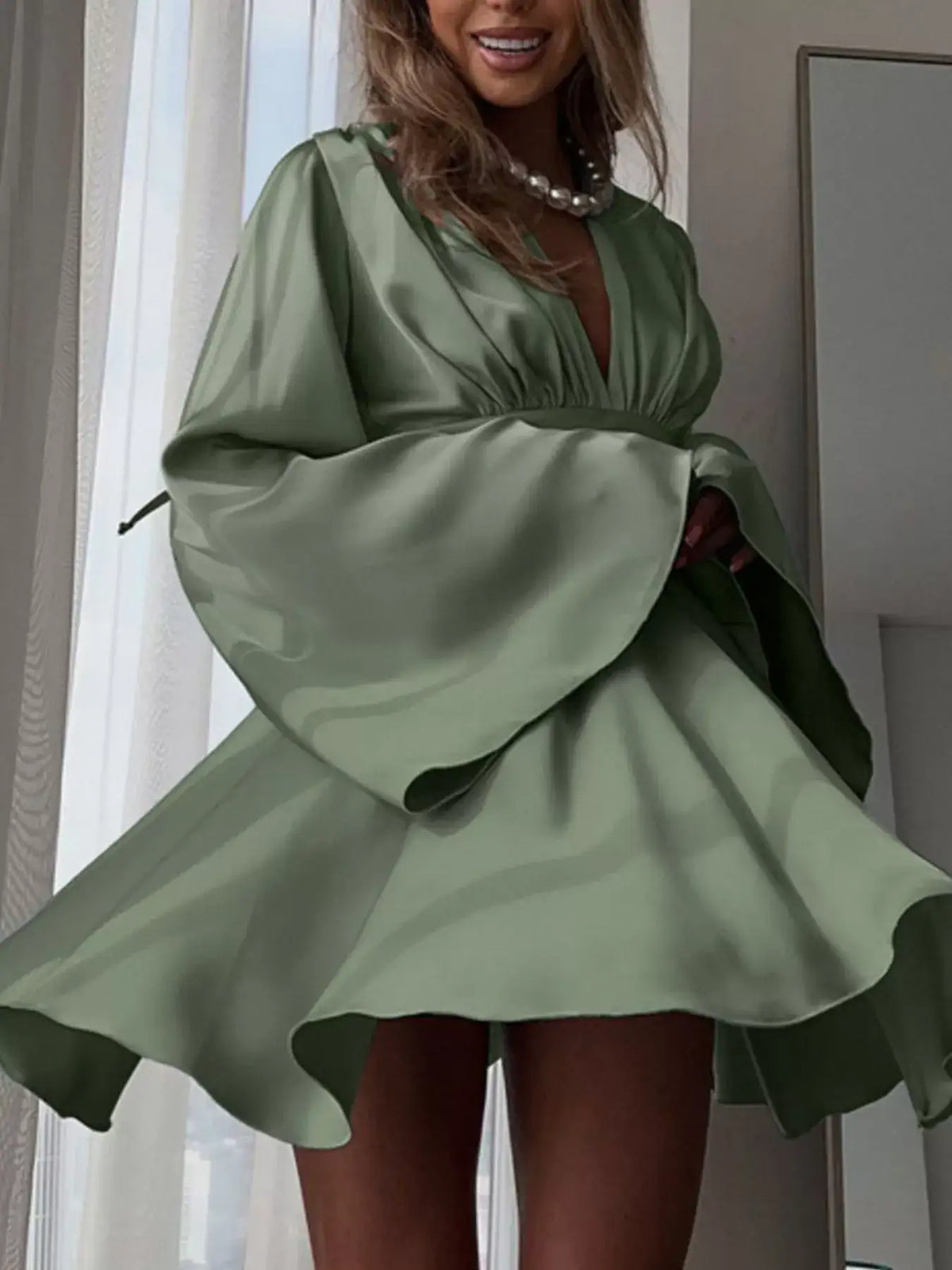 Sage green V-neck satin mini dress by Evie's Dreamland with flowy long sleeves and a flared skirt.