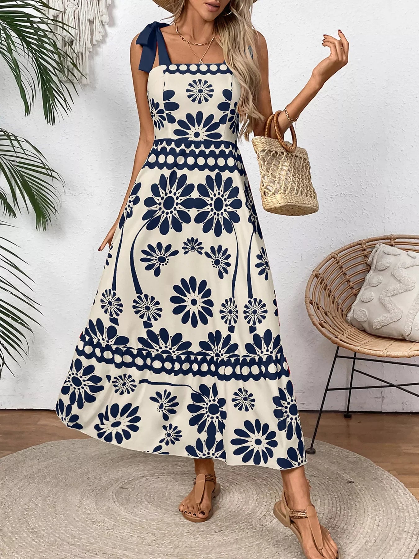 Blue floral maxi dress with bow straps, paired with straw bag and sandals for summer chic style.