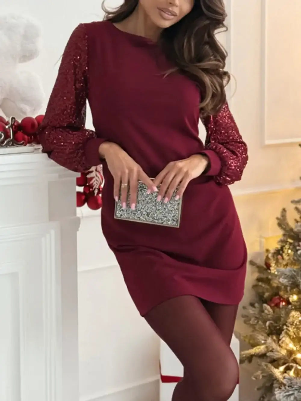 Woman wearing a burgundy long-sleeve mini dress with sequin sleeves from Evie's Dreamland.