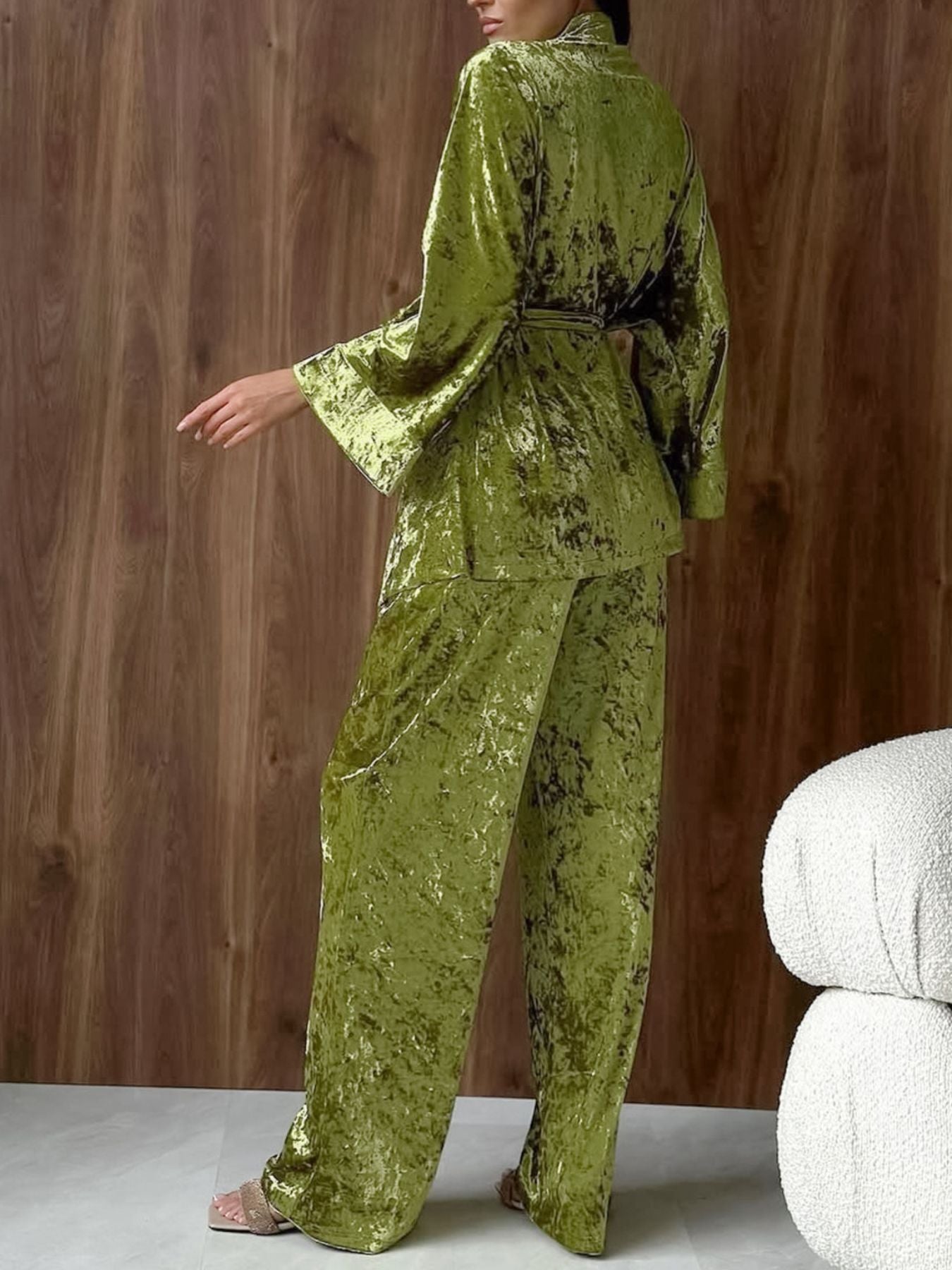 Woman wearing green crushed velvet lounge set with wide-leg pants and belted top