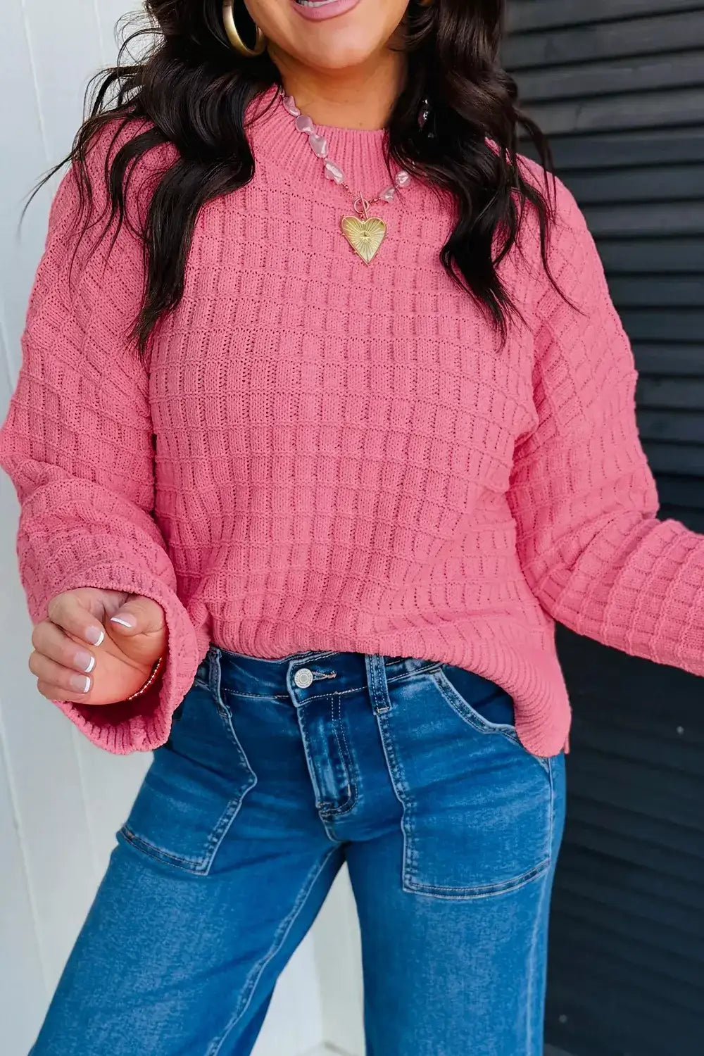 Woman wearing a pink drop shoulder knit sweater with long sleeves and blue jeans from Evie's Dreamland.