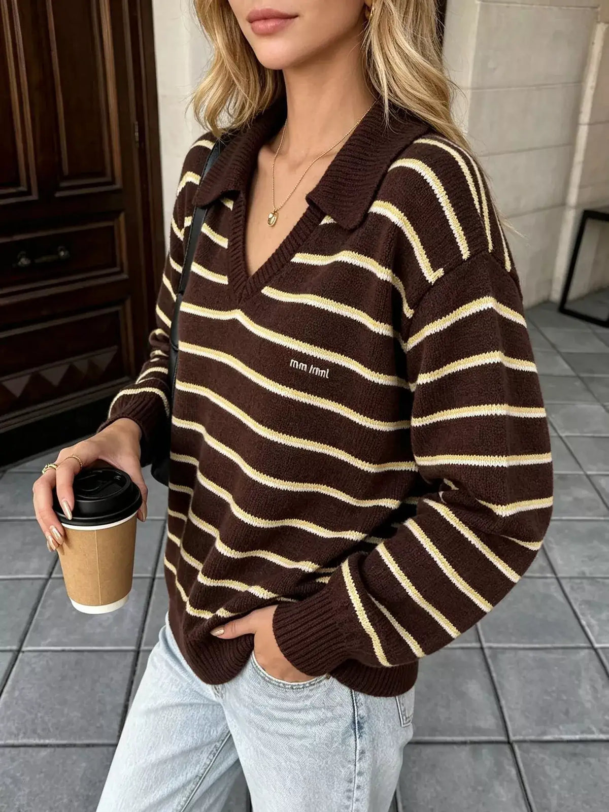 Woman wearing an Evie's Dreamland brown and tan striped polo collar sweater with light blue jeans.