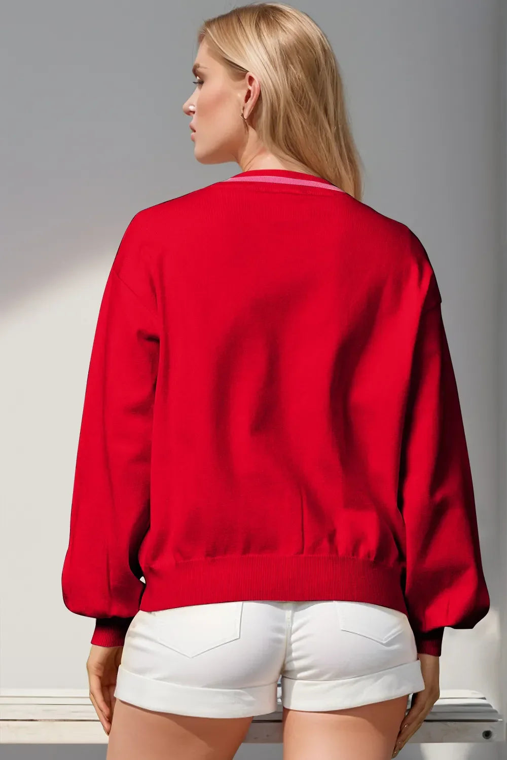 Blonde woman in red long-sleeve sweater and white shorts, back view in bright setting