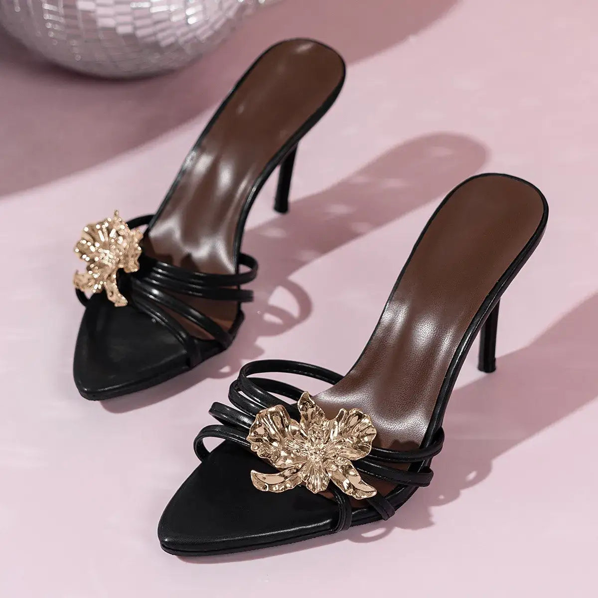 Black open toe stiletto heeled sandals by Evie's Dreamland with gold floral embellishments.