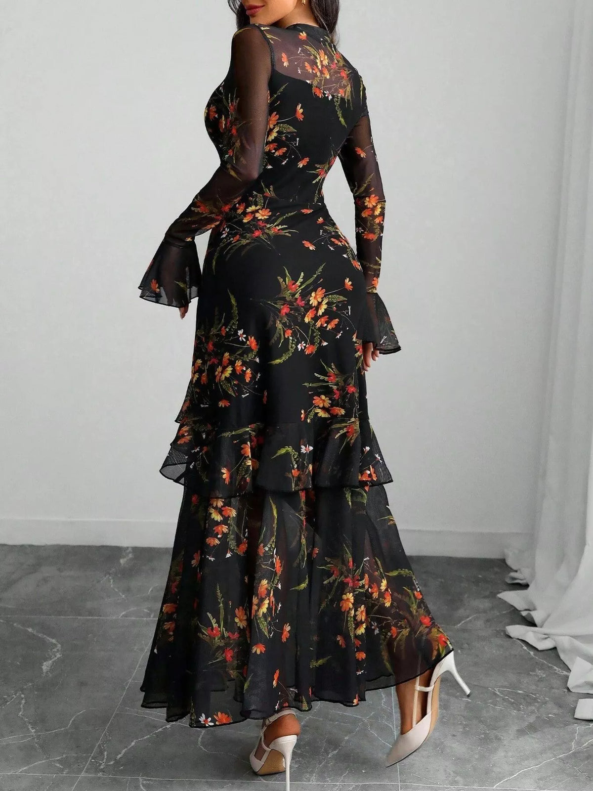 Woman in a black floral print mermaid maxi dress with ruffle sleeves by Evie's Dreamland