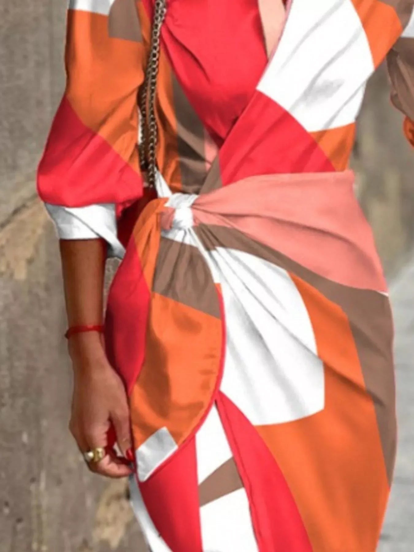 woman wearing a colorful abstract print wrap dress with red, orange, white, and brown geometric patterns