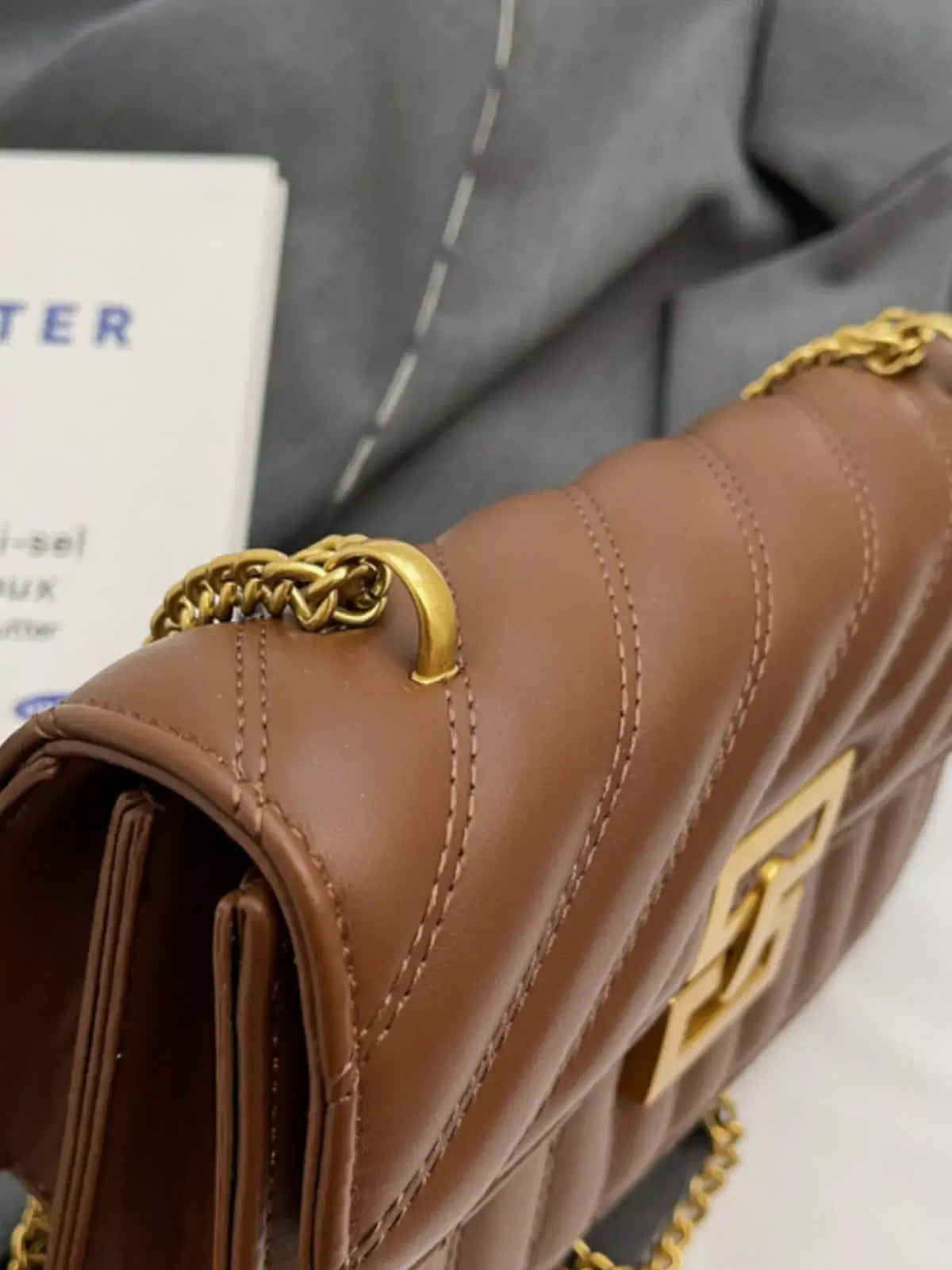 Close-up of a brown quilted flap chain shoulder bag by Evie's Dreamland with gold-tone hardware.