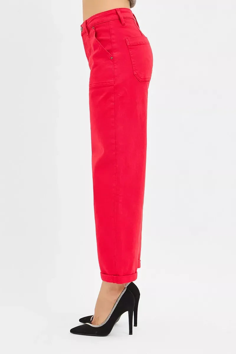 Side view of person wearing red high-waisted pants with black stiletto heels on white background