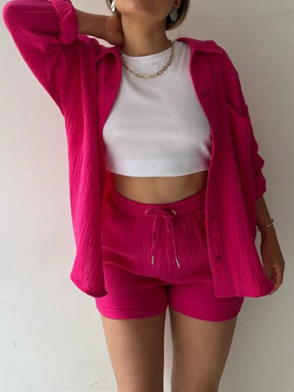 Woman wearing hot pink shirt and shorts set with white cropped tank top, casual fashion