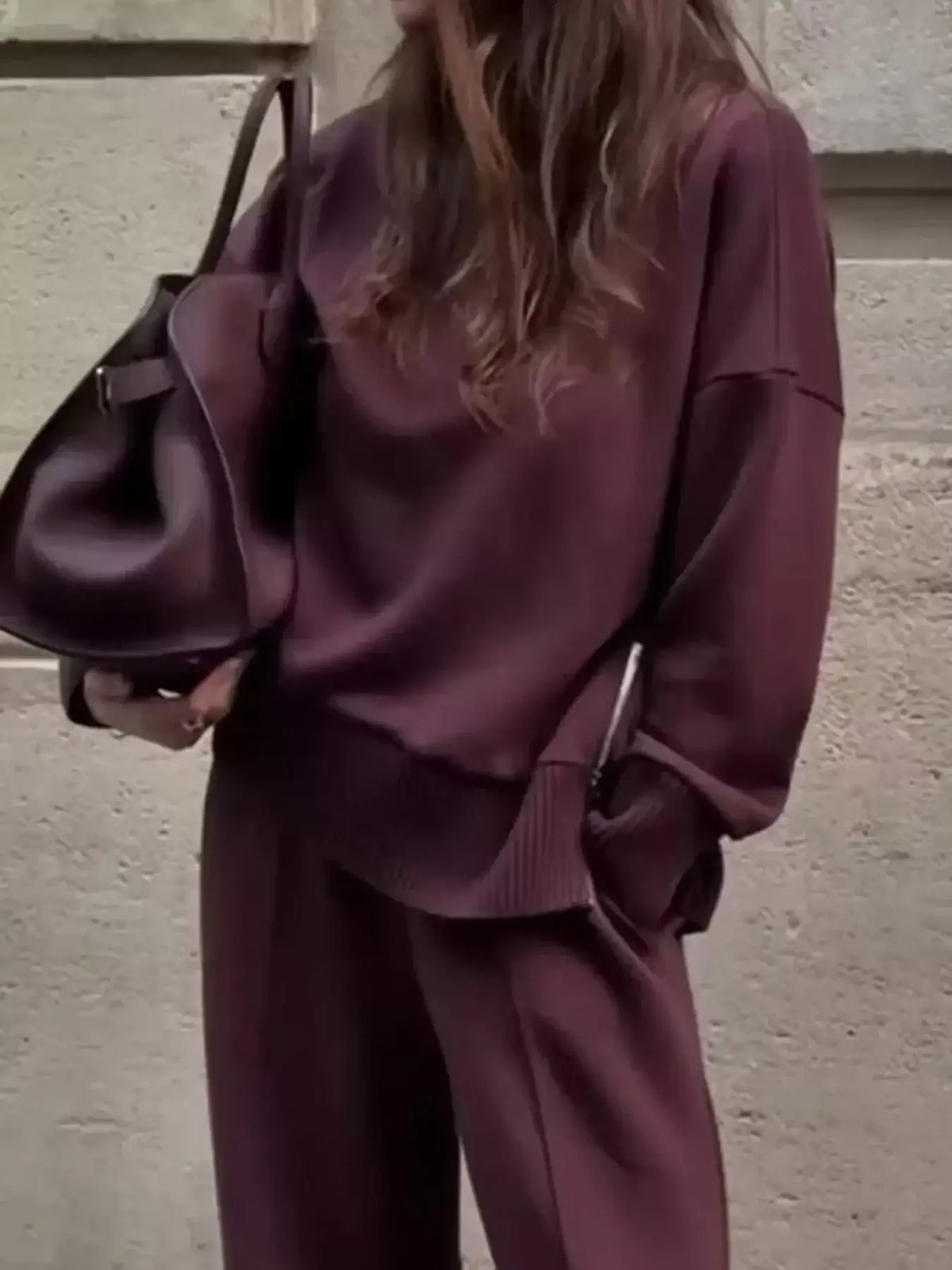 Woman wearing a burgundy ribbed sweatshirt and wide-leg pants set from Evie's Dreamland with a matching bag.
