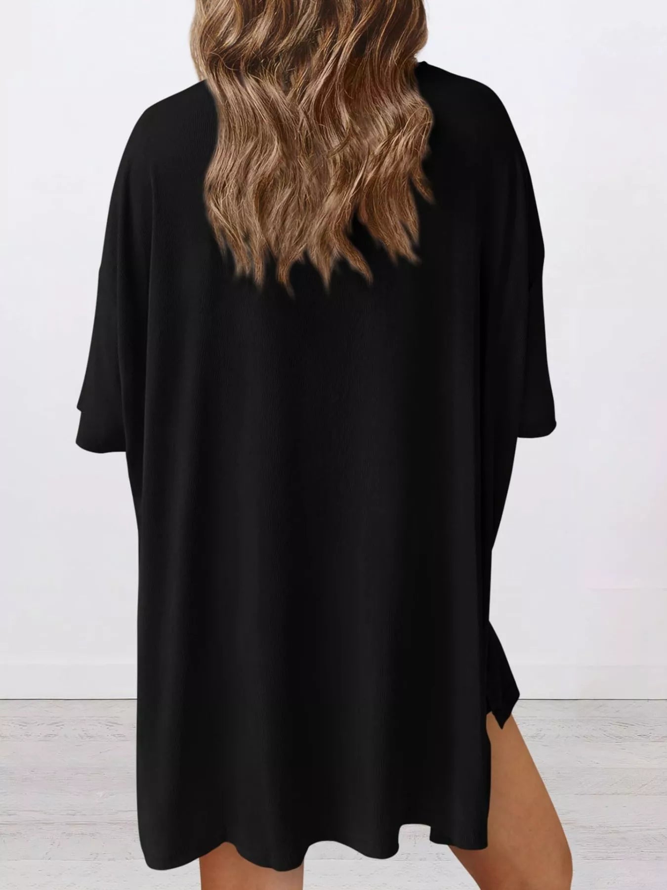 Woman wearing loose black t-shirt dress, back view, casual women's apparel
