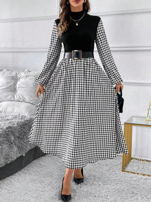 Woman wearing black and white houndstooth midi dress with black belt and black heels in modern room