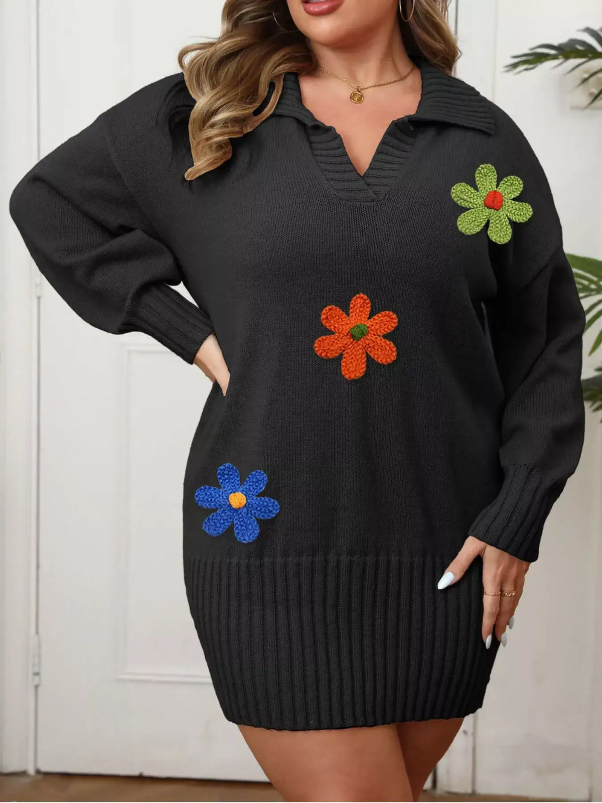 Black plus size ribbed sweater dress by Evie's Dreamland with colorful floral appliques and long sleeves.