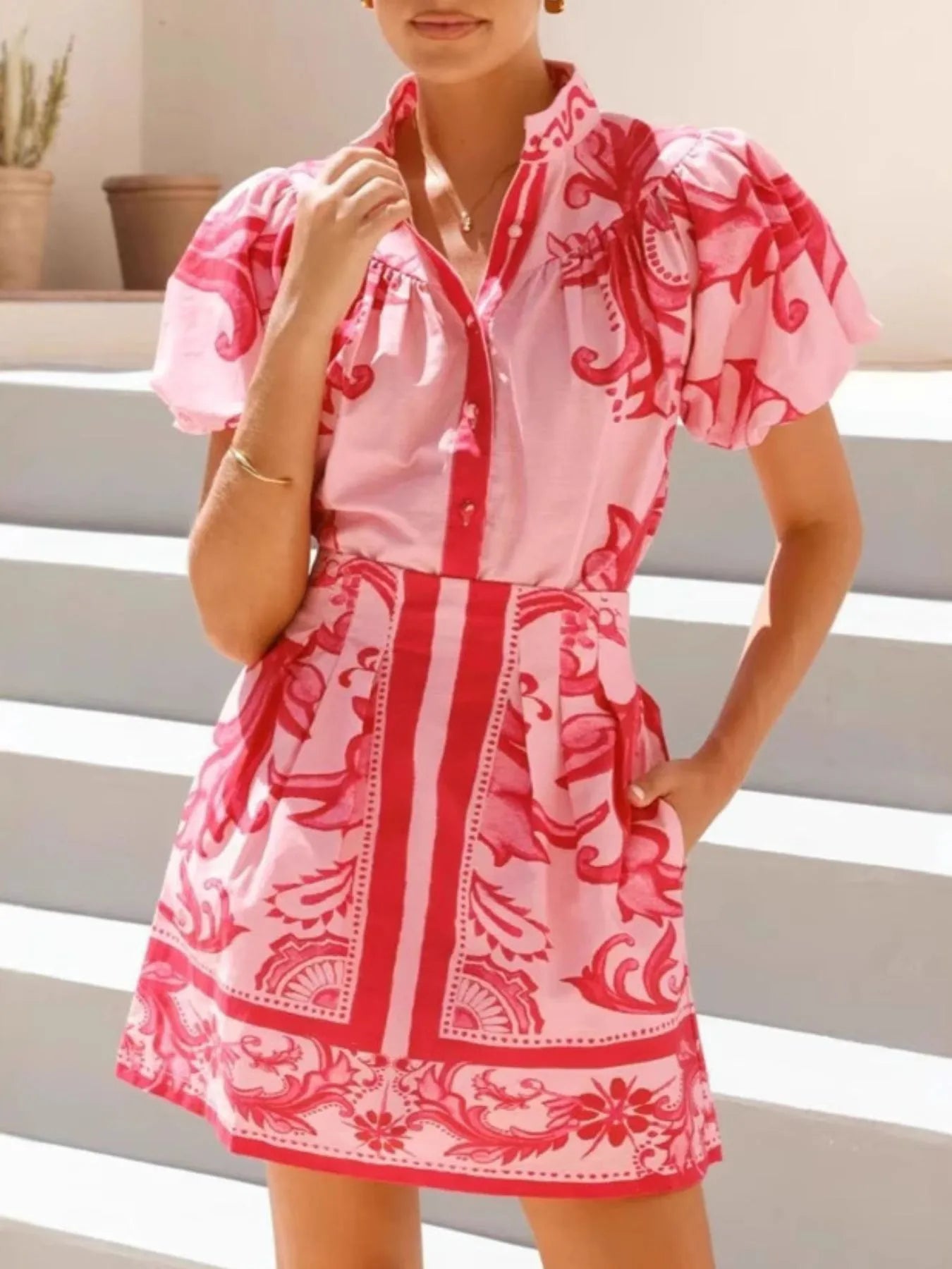 Woman wearing a pink and red floral puff sleeve mini dress in outdoor setting