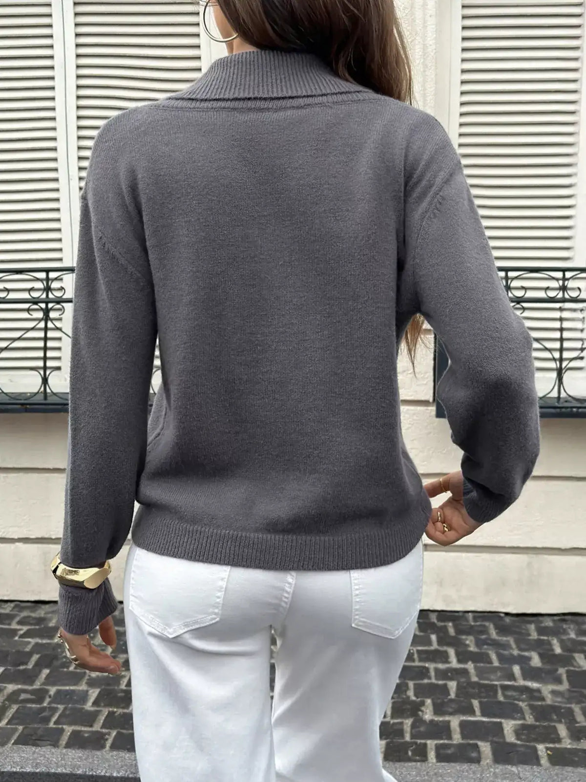 Back view of a charcoal grey shawl collar knit sweater by Evie's Dreamland paired with white pants.