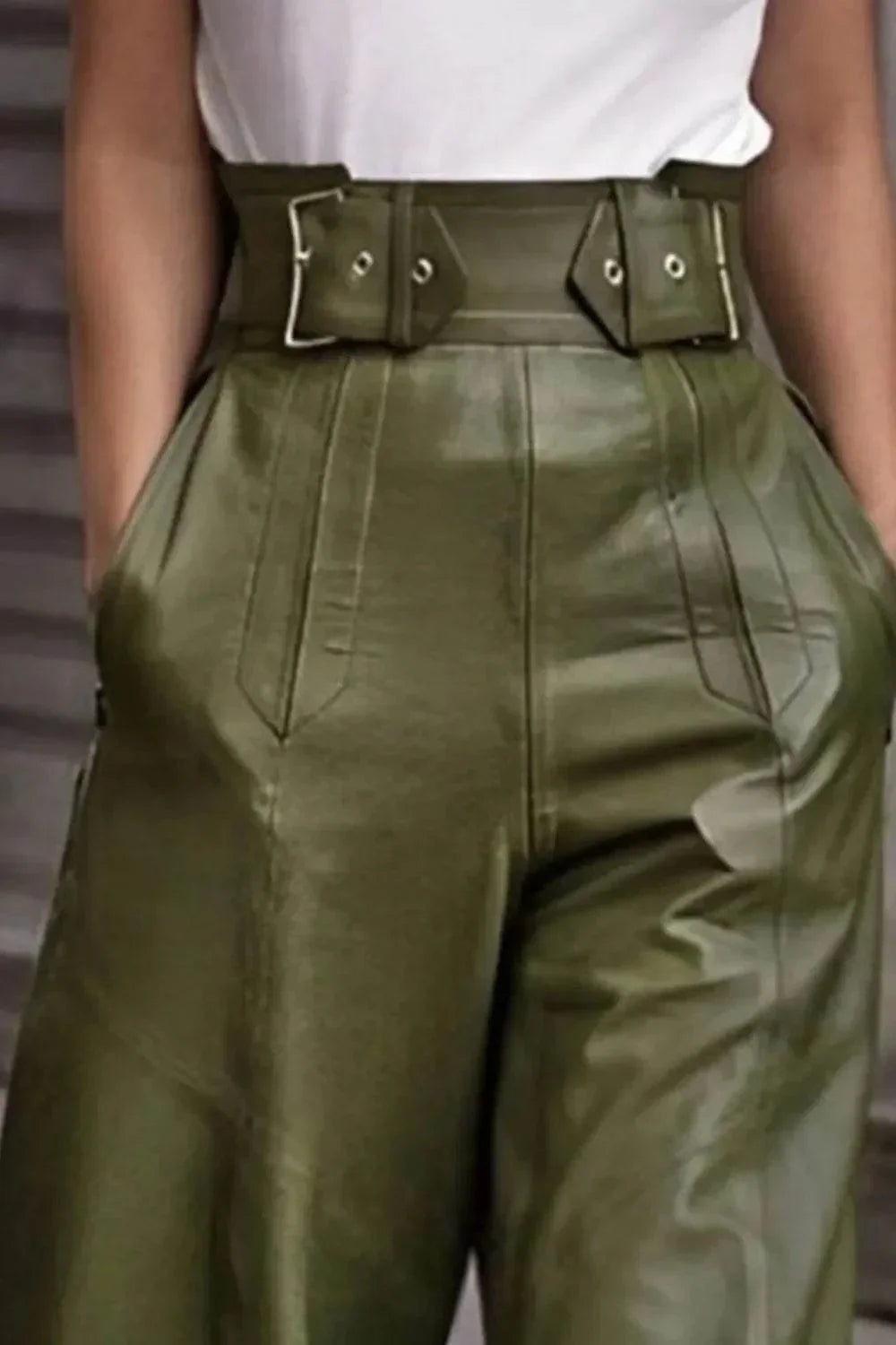 Close-up of high-waisted olive green leather pants with wide belt and pockets, styled with white top