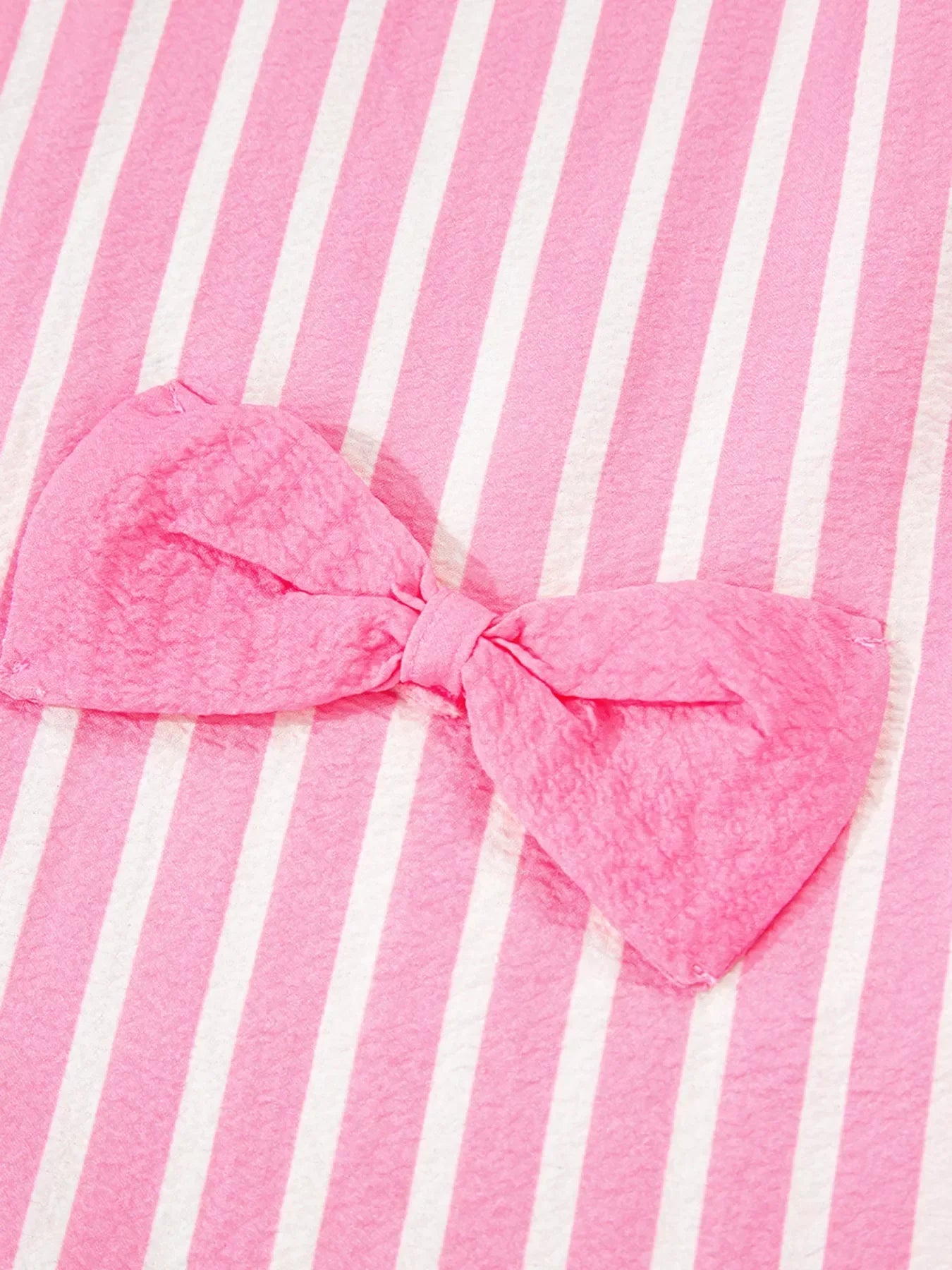 Pink textured fabric bow on a pink and white striped background