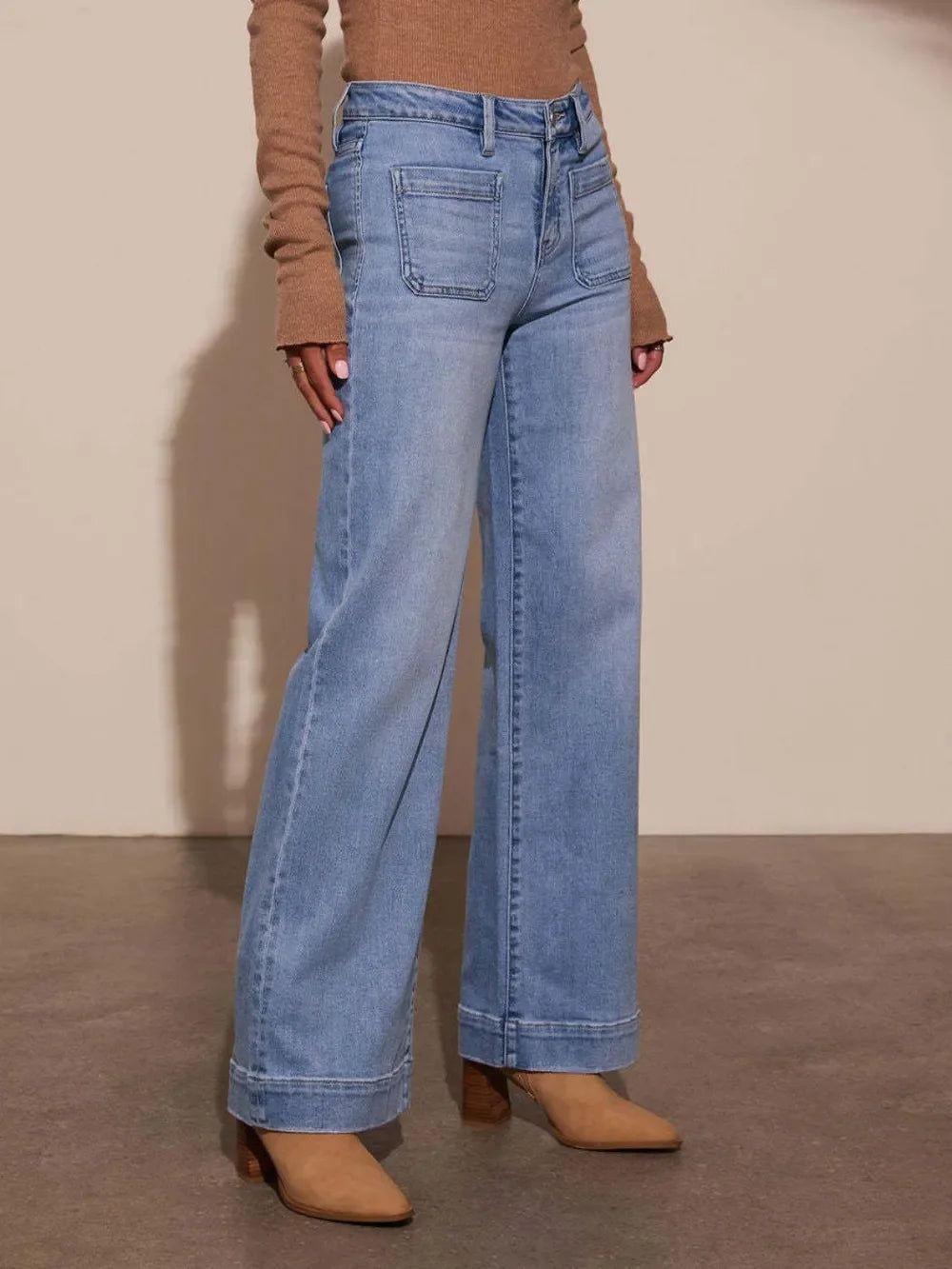 Woman wearing light blue wide-leg jeans with front pockets and tan heeled boots