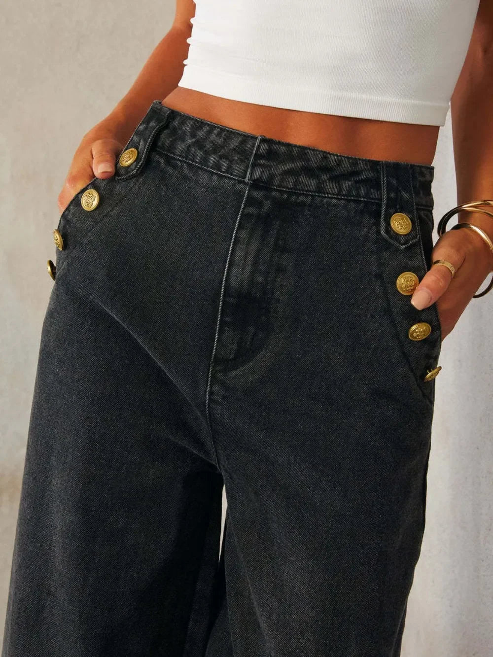 Wide-leg black denim pants with gold side buttons, paired with a white crop top