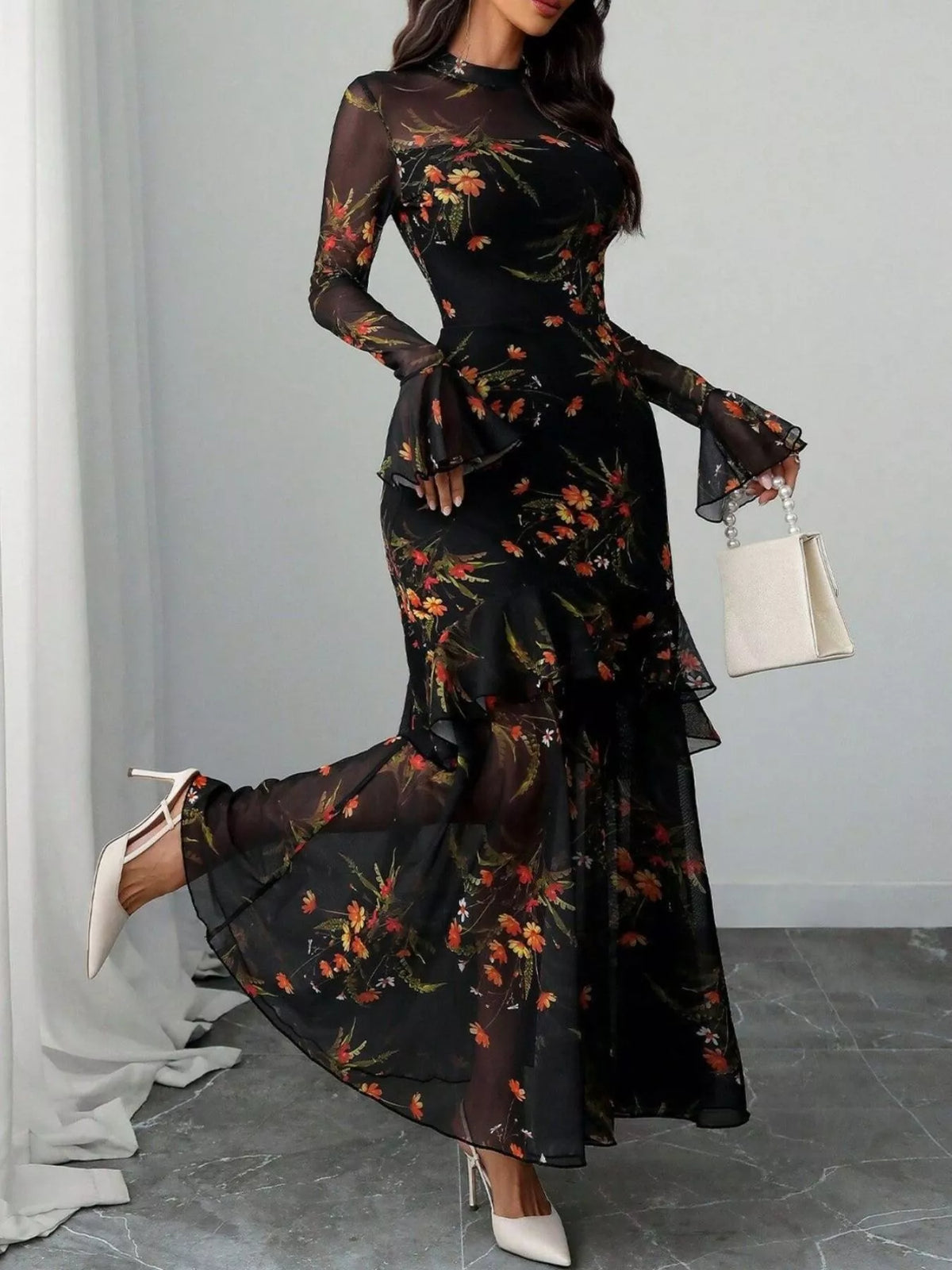 Woman wearing a black floral flounce-sleeve mermaid maxi dress from Evie's Dreamland