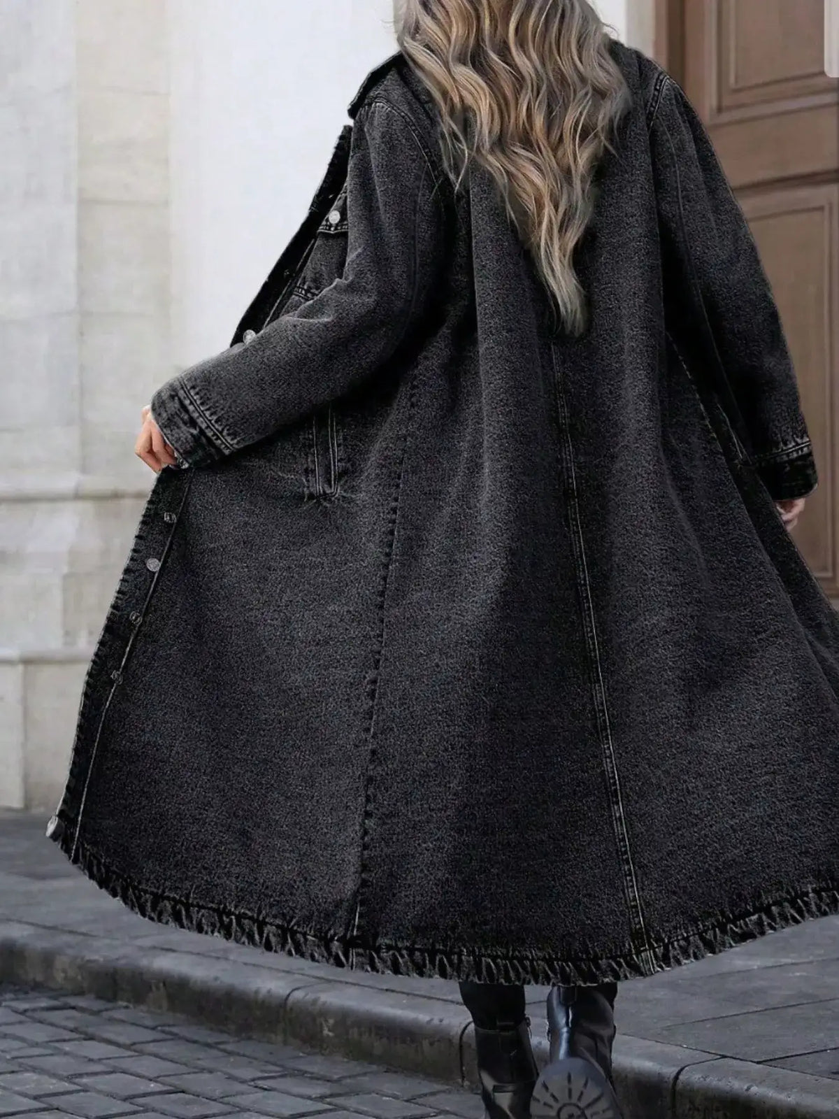 Woman wearing a longline black denim button-front coat with long sleeves from Evie's Dreamland.