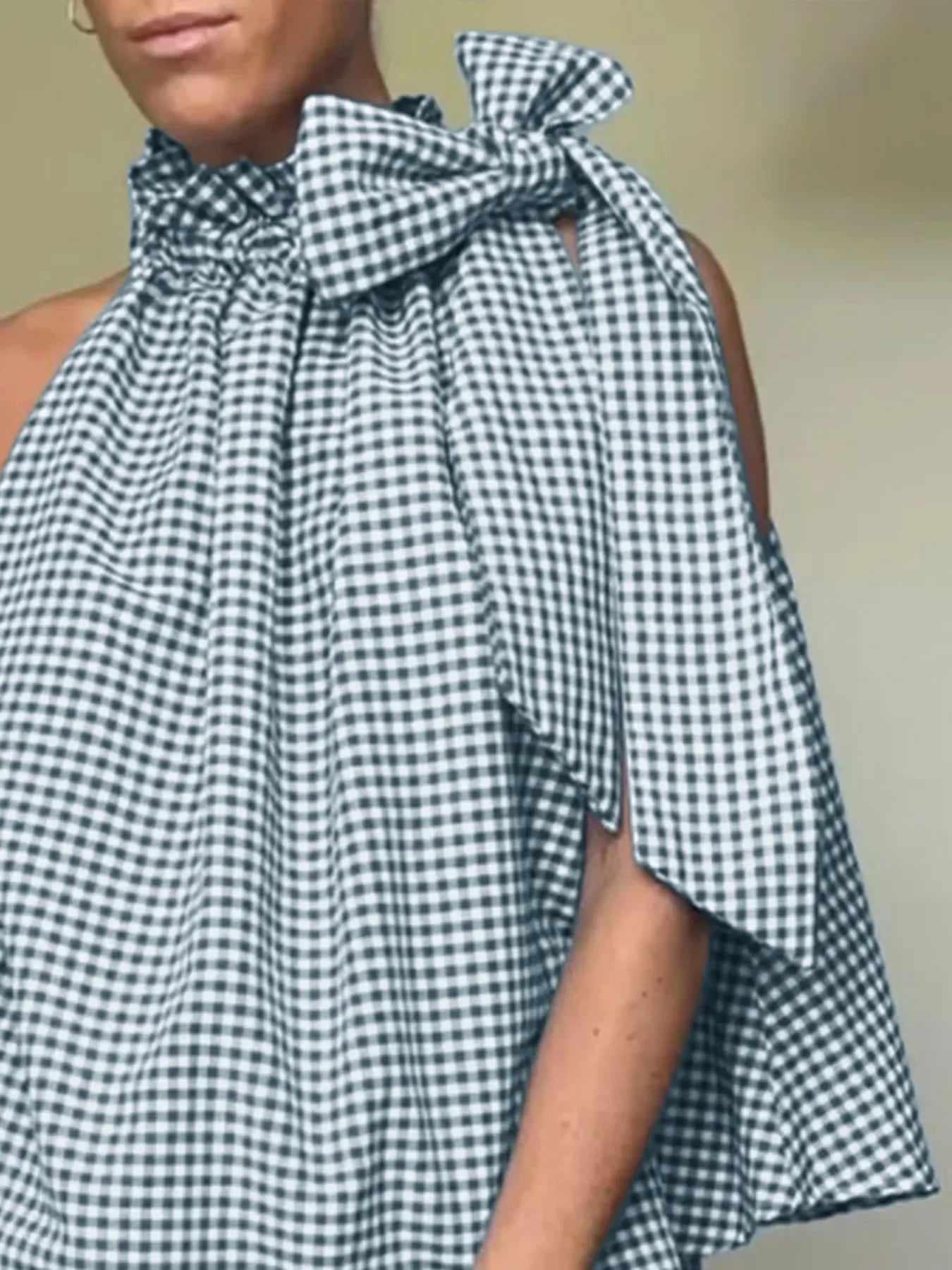 Woman wearing sleeveless gingham halter top with large bow detail, stylish summer blouse