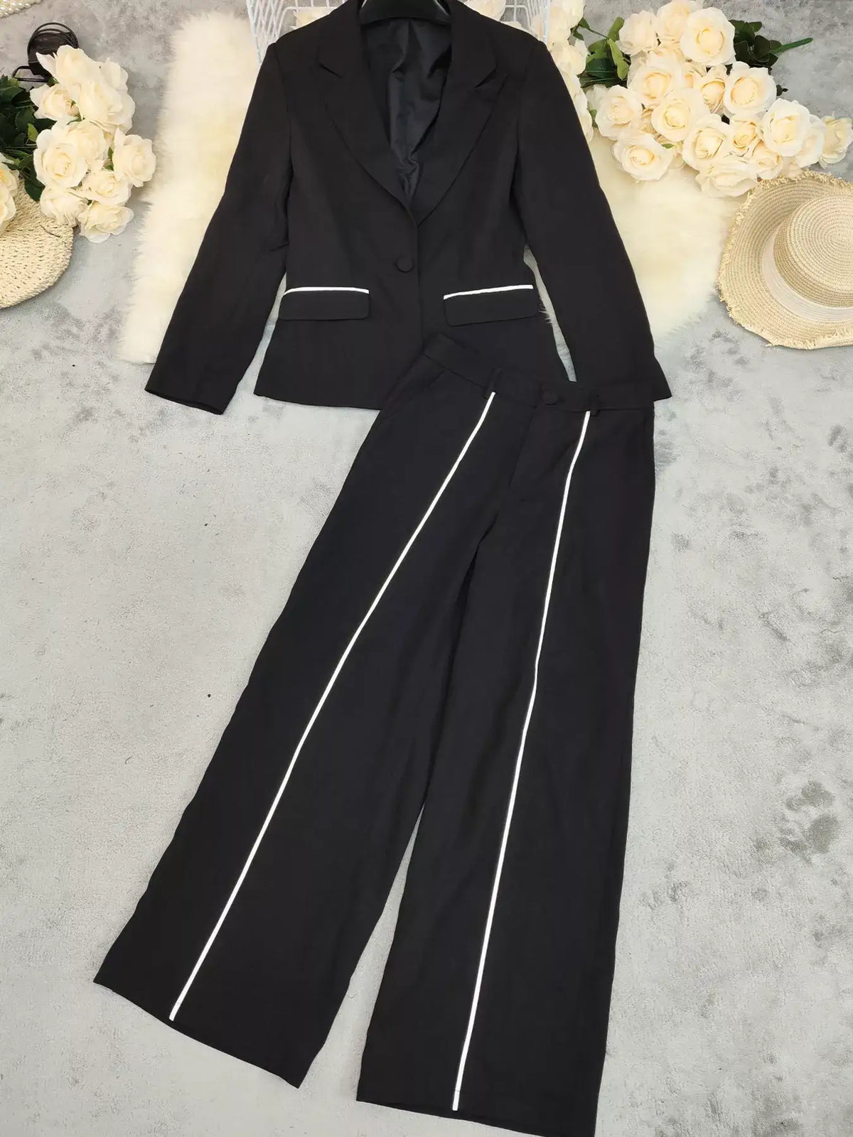 Evie's Dreamland black two-piece suit with white contrast trim blazer and wide leg pants.