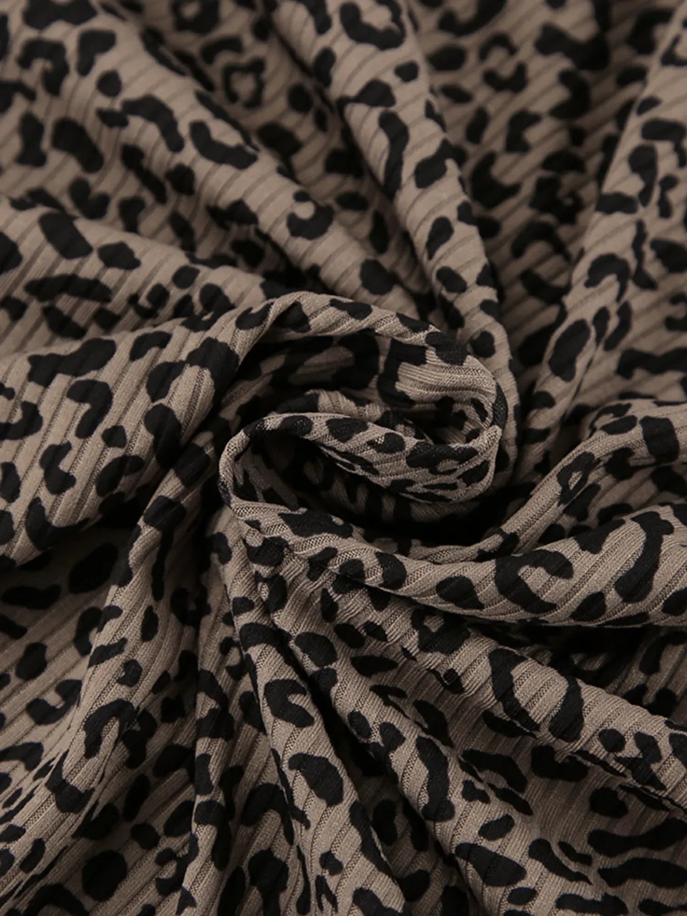 Close-up of beige fabric with black leopard print and textured ribbed pattern