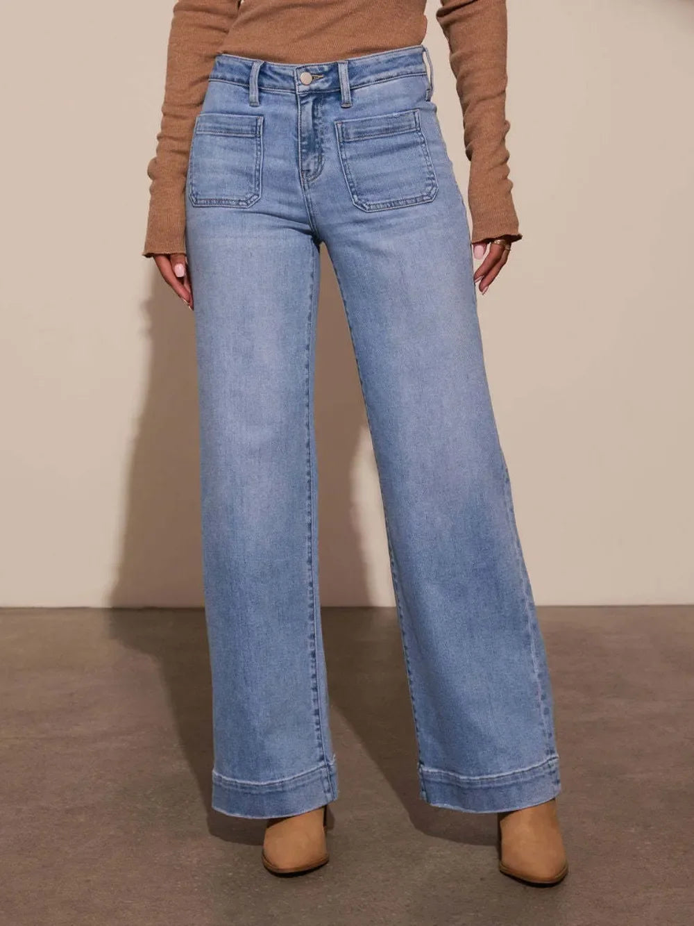 Woman wearing light blue wide-leg jeans with front patch pockets and tan boots