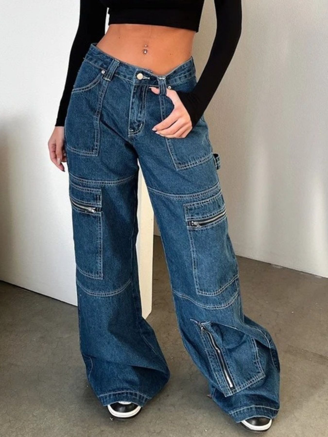 Woman wearing wide-leg patchwork denim cargo jeans with zipper pockets and a crop top