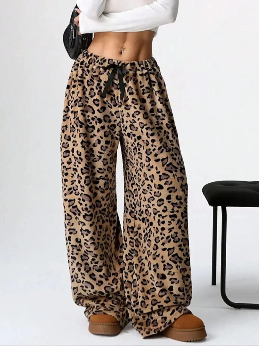 Woman wearing leopard print wide-leg pants with black drawstring and tan platform shoes, styled with white cropped top