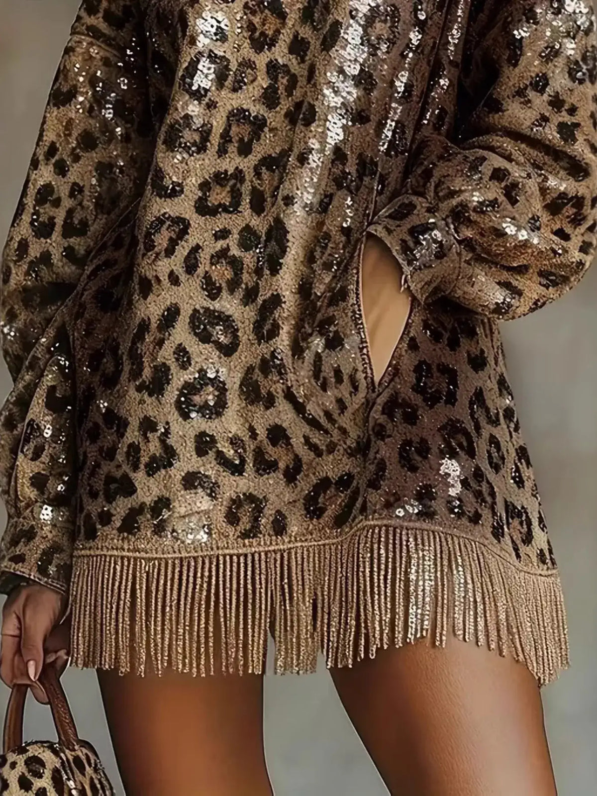 Close-up of Evie's Dreamland leopard print sequin mini dress with fringe hem and long sleeves.