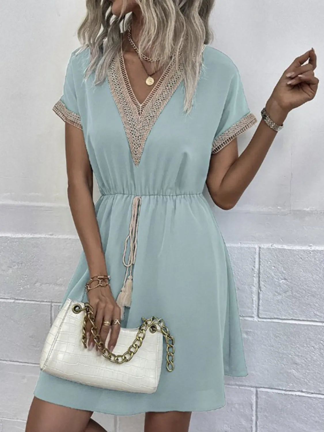 Mint green V-neck dress with lace trim, short sleeves, and drawstring waist, paired with white croc-embossed chain bag