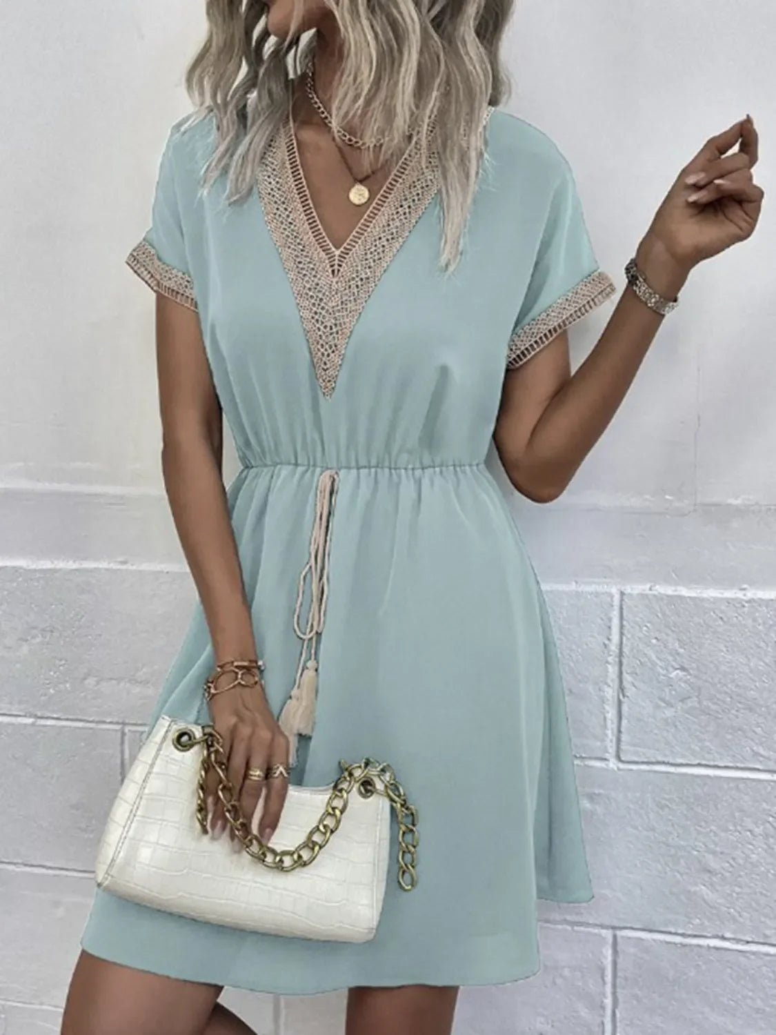 Mint green V-neck dress with lace trim, short sleeves, and drawstring waist, paired with white croc-embossed chain bag