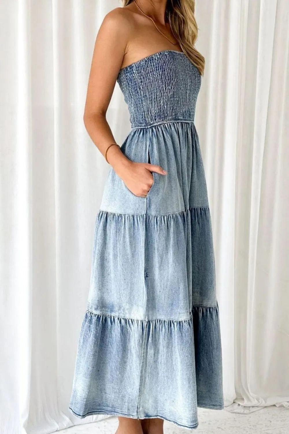 Woman wearing a strapless tiered denim midi dress with pockets, casual fashion style