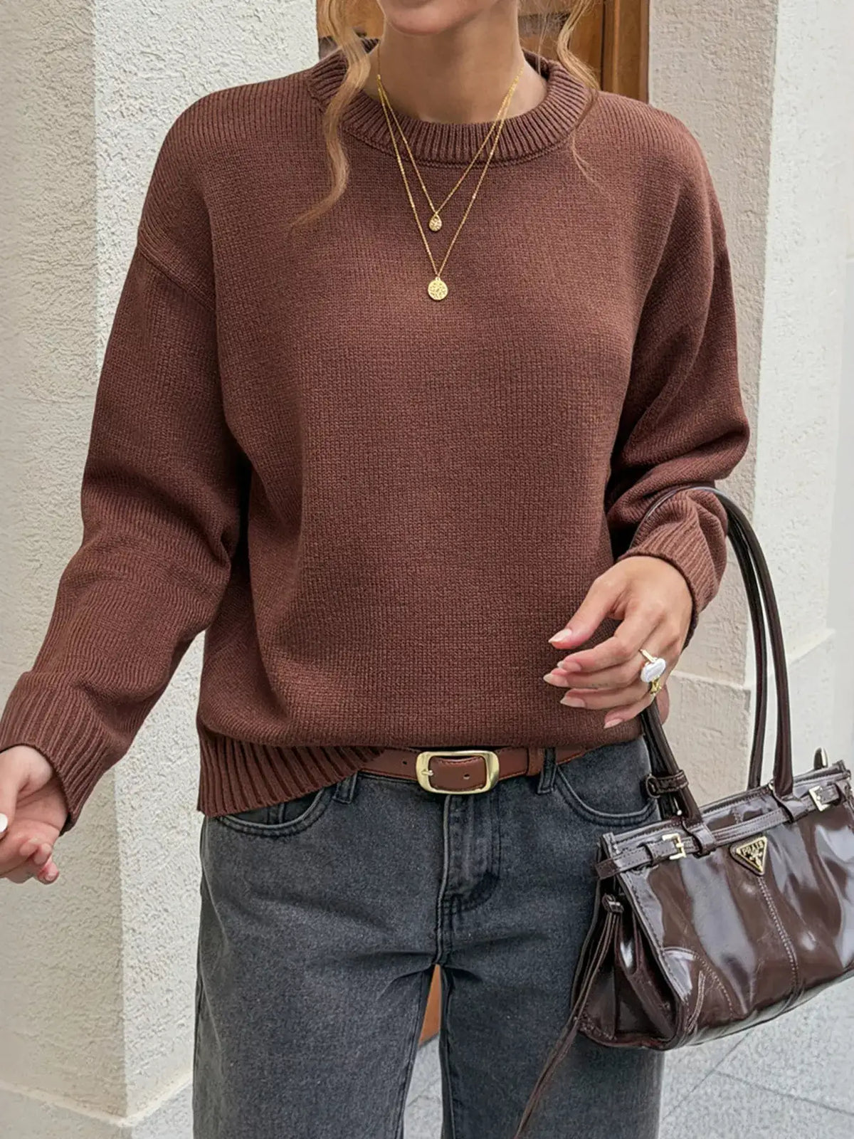 Woman wearing a brown crew neck ribbed hem sweater by Evie's Dreamland with grey jeans and a brown handbag.