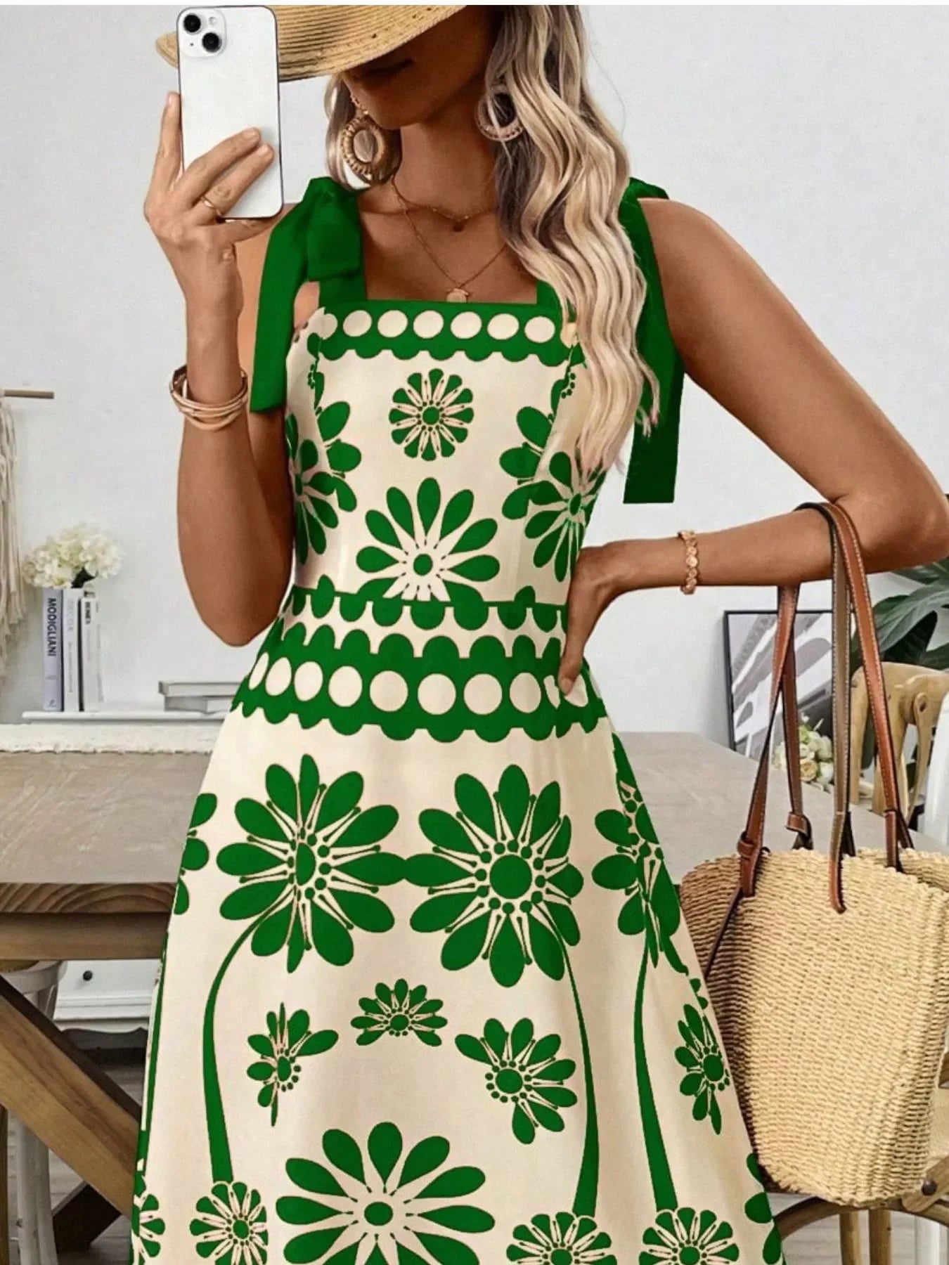 Green floral print dress with bow straps, styled with straw hat and woven bag for summer elegance.