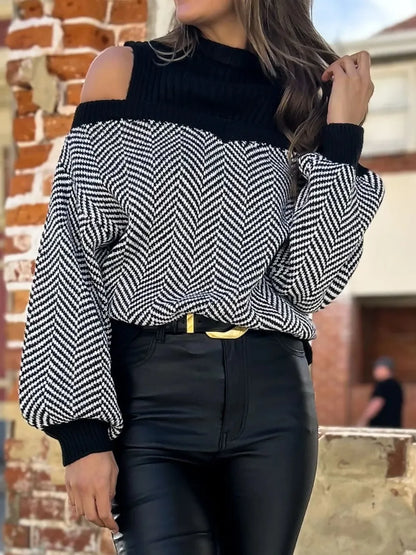 Woman wearing black and white chevron knit cold-shoulder sweater with black high-waisted pants outdoors
